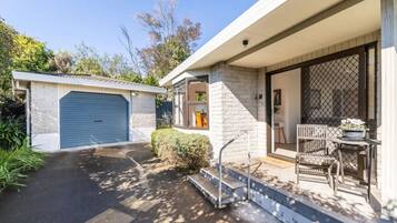 A residential property with a garage, a covered porch with outdoor seating, and a small garden area.