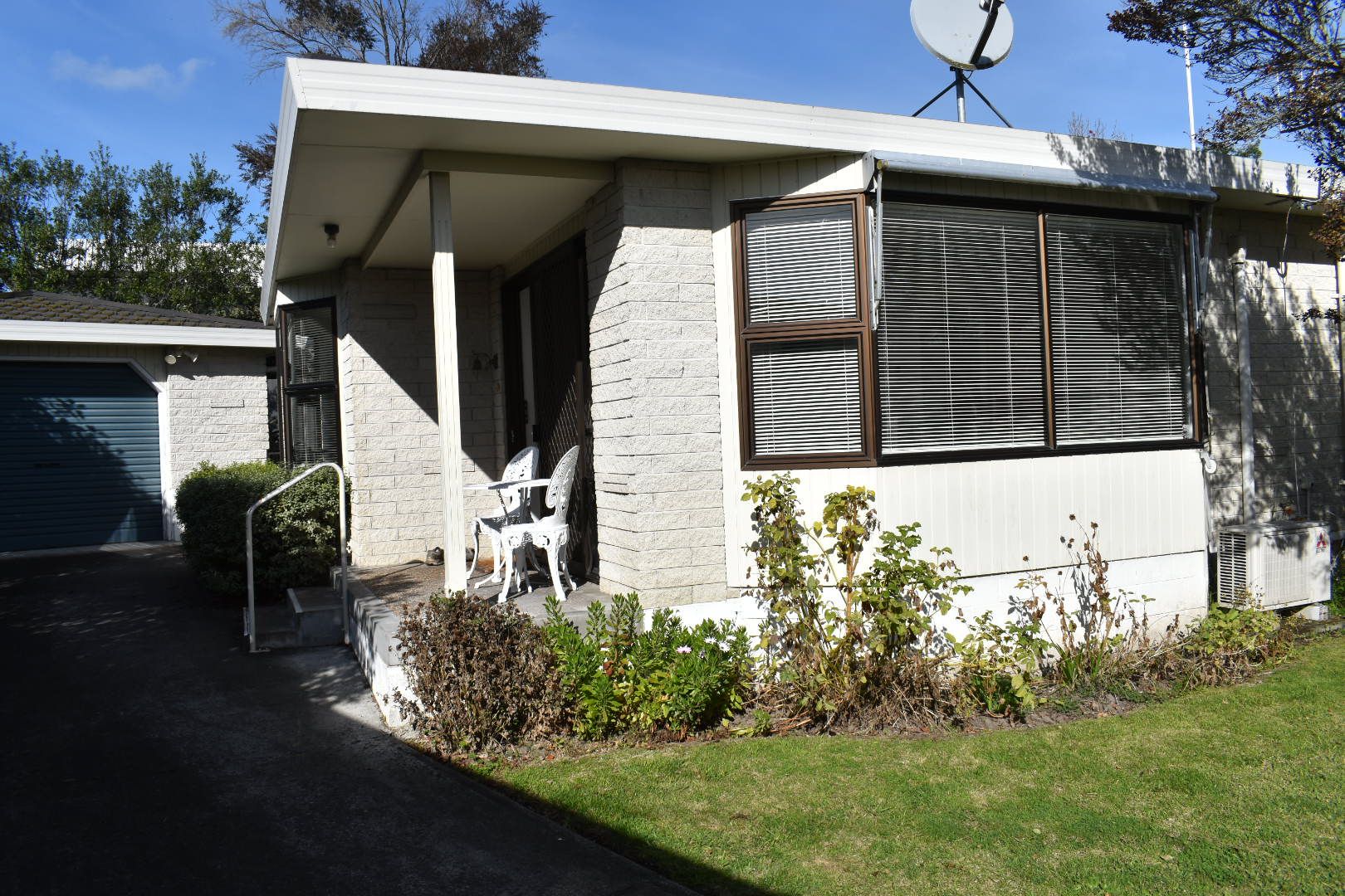A residential house with a garage, a covered porch, and a satellite dish.