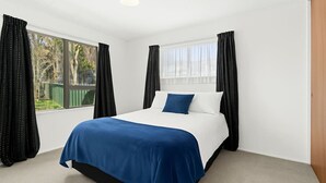 A bedroom with a bed, large windows, and curtains. - Havelock North Heartbeat (Havelock North)