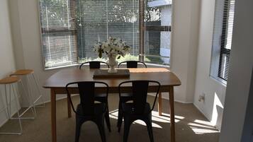 A dining area with a wooden table, four chairs, and a vase of flowers.