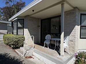 A house with a porch, two white chairs, and a small table.