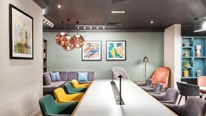 A modern meeting room with a long table, comfortable seating, and artwork on the walls. - Holiday Inn LEEDS - WAKEFIELD M1, JCT.40 by IHG (Wakefield)