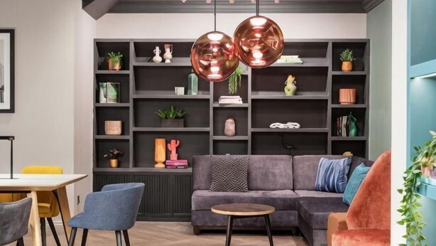 A modern living room with a sofa, chairs, a coffee table, and a bookshelf filled with decorative items. - Holiday Inn LEEDS - WAKEFIELD M1, JCT.40 by IHG (Wakefield)