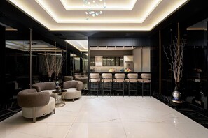 A modern interior with a bar area, seating, and a kitchen. - Apartment 1+1 Qoople Legend A12 100 m from the sea (Alanya)