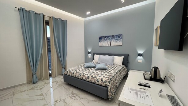 Una camera da letto moderna con un letto, una scrivania e una televisione.
