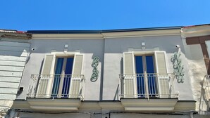 Facciata di un edificio con due finestre, ciascuna con balcone e persiane.