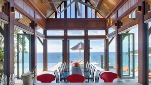 Un espace repas offrant une vue sur la mer, comprenant une table avec des chaises et un vase décoratif.
