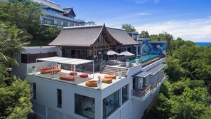 Ein modernes Mehrfamilienhaus mit Dachterrasse, Schwimmbad und üppiger, umliegender Bepflanzung.