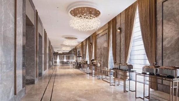 A long, elegant corridor with a marble floor, large windows, and a series of tables with chairs. - Crowne Plaza LUCKNOW by IHG (Chak Kajehra)