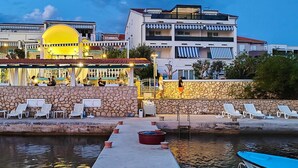 Hotel à beira-mar com piscina, espreguiçadeiras e restaurante com área externa.