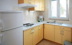 A kitchen with a refrigerator, stove, sink, and window with blinds. - Beautiful apartment in Stara Novalja with heated swimming pool (Stara Novalja)