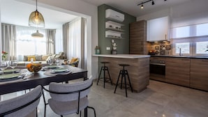Una cucina moderna con zona pranzo, caratterizzata da un'isola centrale con sgabelli, illuminazione a sospensione ed elettrodomestici integrati.