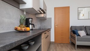 A compact kitchen with a coffee maker, fruit bowl, and a wooden door. - Stunning apartment in Silo with WiFi (Silo)