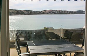 A balcony with a table and chairs overlooking a calm lake and distant mountains. - Apartment in Stara Novalja (135) (Stara Novalja)