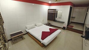 Un dormitorio con cama, mesita de noche, armario, espejo y zona de ducha.
