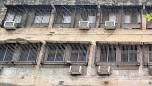 Un edificio de varios pisos con varias unidades de aire acondicionado y ventanas protegidas con rejas.