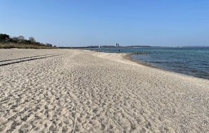 A sandy beach with a clear view of the sea and distant buildings. - 2 bedroom cozy home in Timmendorfer Strand OT (Timmendorfer Strand OT)