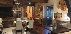 A cozy restaurant with wooden furniture, a brick wall, and a bar area with bottles and glasses. - Hôtel restaurant l'Eolienne (Rouxmesnil-Bouteilles)