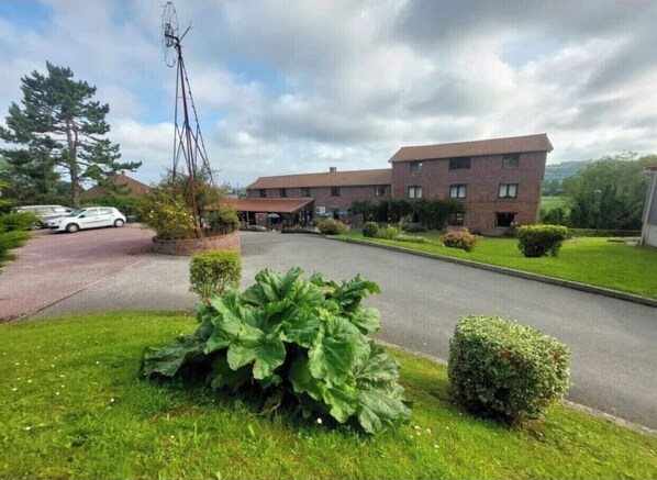 A residential building with a driveway, a large bush, and a small hedge. - Hôtel restaurant l'Eolienne (Rouxmesnil-Bouteilles)