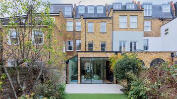 A modern two-story building with a glass entrance and a small garden area.