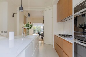 A modern kitchen with a central island, stainless steel appliances, and pendant lighting. - Impeccably Designed 5BD Family Home in West London (Greater London)
