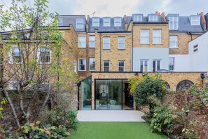 A modern two-story building with a glass entrance and a small garden area. - Impeccably Designed 5BD Family Home in West London (Greater London)