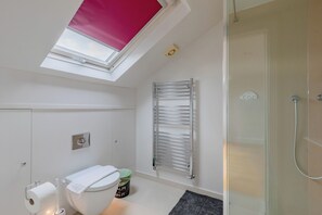A modern bathroom with a skylight, a glass shower enclosure, and a towel rack. - Impeccably Designed 5BD Family Home in West London (Greater London)