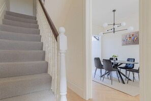 A staircase with a white balustrade leading to a dining area with a table and chairs.
