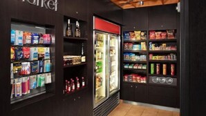 Un petit espace de vente avec des étagères remplies de divers produits, un présentoir réfrigéré et une enseigne indiquant « marché » sur le mur.