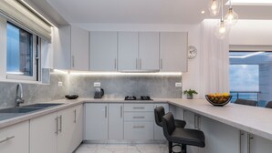 Una cucina moderna con un piano di lavoro in marmo, mobili a scomparsa, piano cottura a gas e zona pranzo con sgabelli da bar.