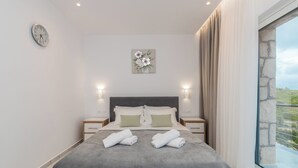 Una camera da letto moderna con un letto grande, due comodini, una sveglia a parete e una finestra con tende.
