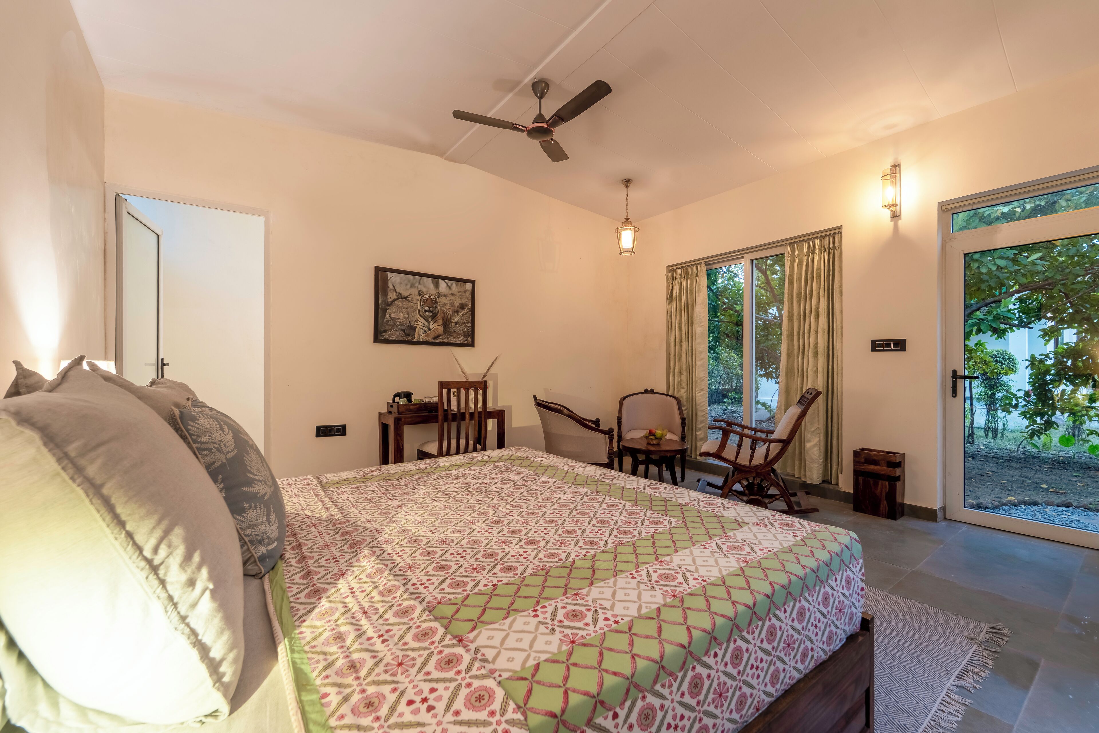 Ein Schlafzimmer mit Bett, Deckenventilator, Schreibtisch, Stuhl und einem Fenster mit Vorh ängen.