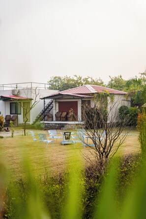 Una casa con techo rojo, una escalera que lleva a un porche y varias sillas de exterior.