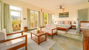 A spacious room with a bed, a sofa, a wooden coffee table, and a dining table. - The Rann Baagh Ranthambore (Sawai Madhopur)