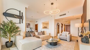 A modern living room with a sofa, armchair, coffee table, and a potted plant. - High Floor with Direct Burj Khalifa and Fountain Views (Dubai)