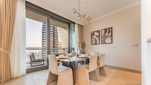 A modern dining area with a large table, four chairs, and a view of a cityscape through a glass door. - High Floor with Direct Burj Khalifa and Fountain Views (Dubai)
