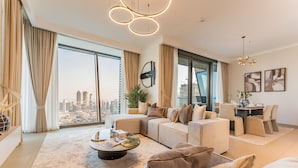 A spacious living room with a large window, a sofa set, a coffee table, and a dining area with chairs. - High Floor with Direct Burj Khalifa and Fountain Views (Dubai)