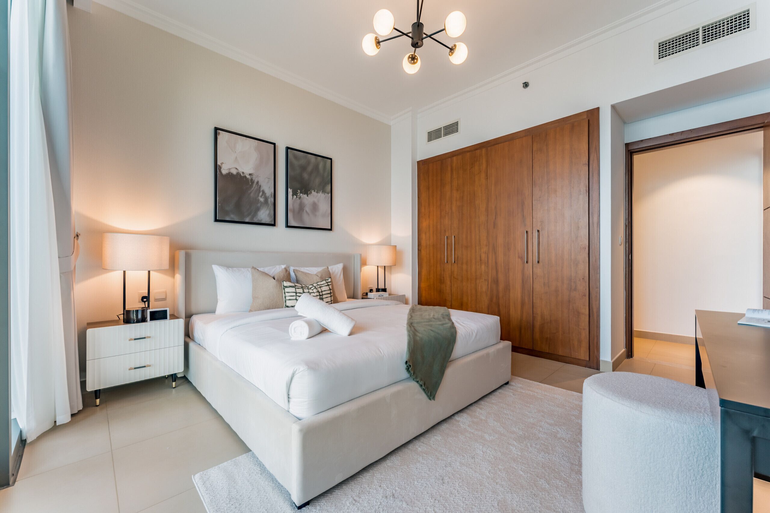 A modern bedroom with a large bed, bedside tables, a wardrobe, and a desk.