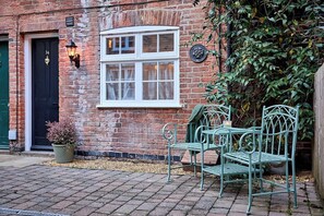 A brick building with a black door, a white window, and a green metal chair outside. - 3-Bed Historic Knitters House in Nottingham (Nottingham)