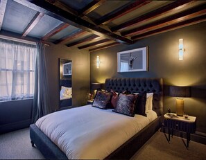 A bedroom with a large bed, a nightstand, a wall-mounted lamp, and a window with curtains. - 3-Bed Historic Knitters House in Nottingham (Nottingham)