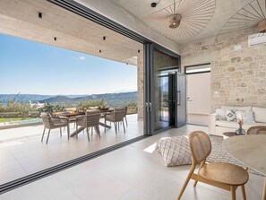 Un espacio de sala-comedor moderno y abierto, con un juego de mesa, sofá y vistas a las montañas.