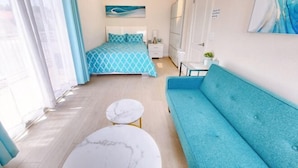 A bedroom with a bed, a blue sofa, a small table, and a painting on the wall. - Beautiful Yard 7 Rooms 4 Bathrooms Near Disneyland (Hacienda Heights)