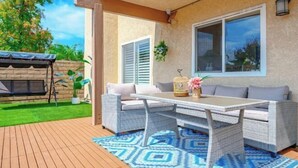 An outdoor patio with wicker furniture, a table, and a blue patterned rug. - Beautiful Yard 7 Rooms 4 Bathrooms Near Disneyland (Hacienda Heights)