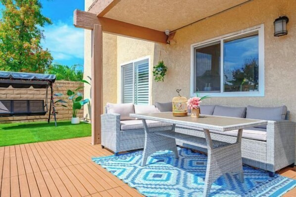 An outdoor patio with wicker furniture, a table, and a blue patterned rug. - Beautiful Yard 7 Rooms 4 Bathrooms Near Disneyland (Hacienda Heights)