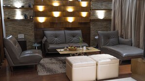 A modern living room with leather sofas, a coffee table, and a stone accent wall. - Hotel Prachi (Bhubaneshwar)