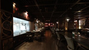 A dimly lit restaurant with wooden floors and tables. - Hotel Prachi (Bhubaneshwar)