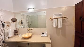A bathroom with a beige sink, a large mirror, and a towel rack with folded towels.