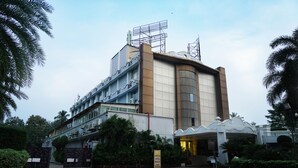 A hotel with a modern architectural design, featuring a curved facade, multiple floors, and a prominent entrance with a covered walkway. - Hotel Prachi (Bhubaneshwar)