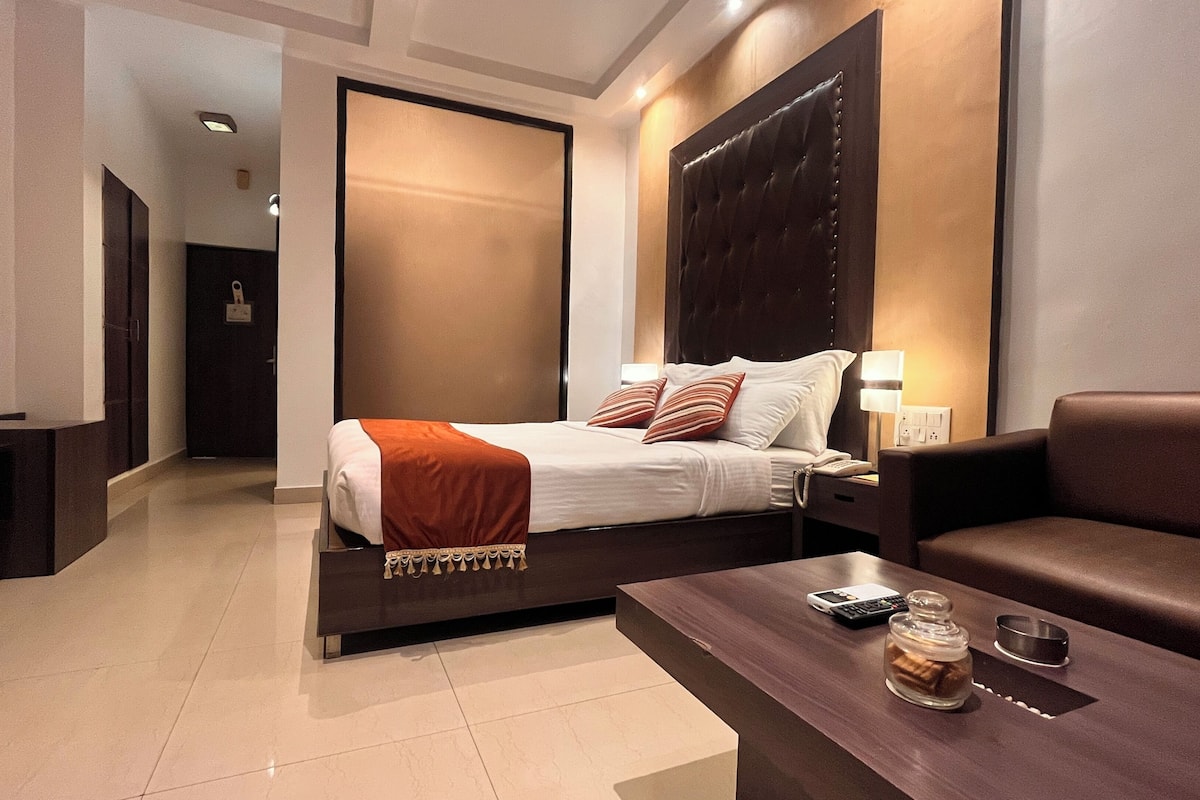 A hotel room with a bed, bedside table, and a sofa.