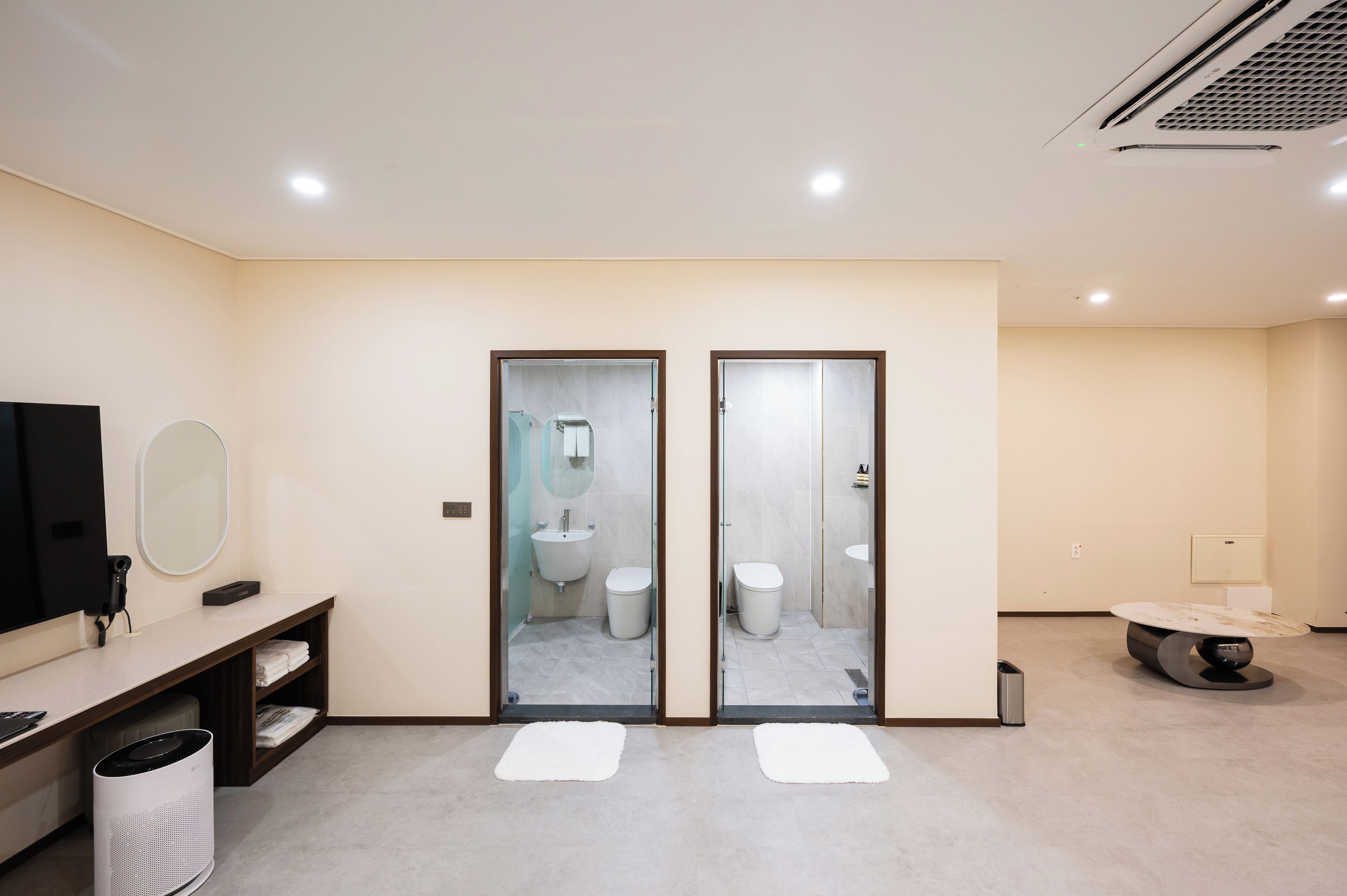 Un baño moderno con tocador, espejo y dos inodoros.